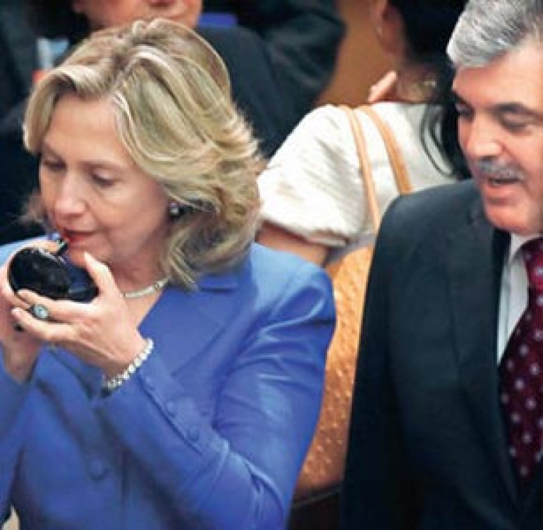 US Sec. of State Hillary Clinton uses lipstick while talking to Abdullah Gul 