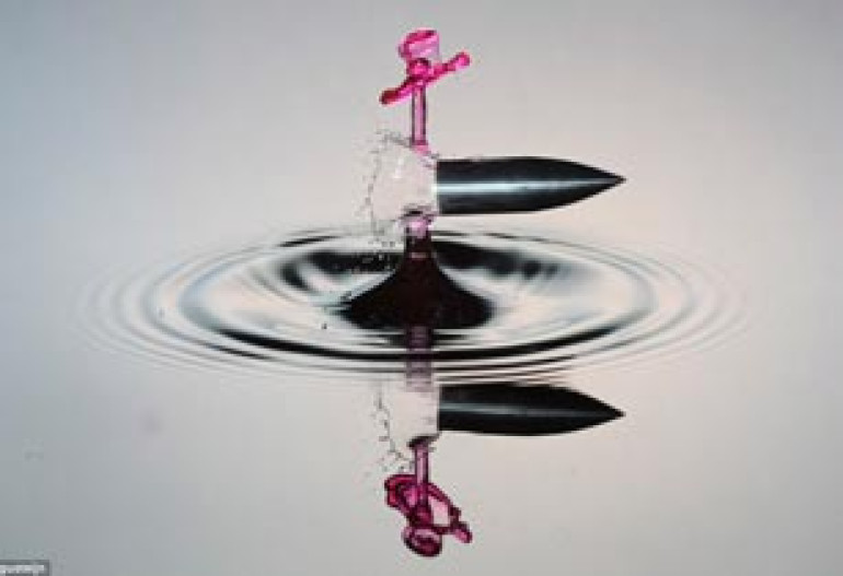 Water shot! Photographer captures the precise moment a speeding bullet pierces a tiny droplet of falling liquid